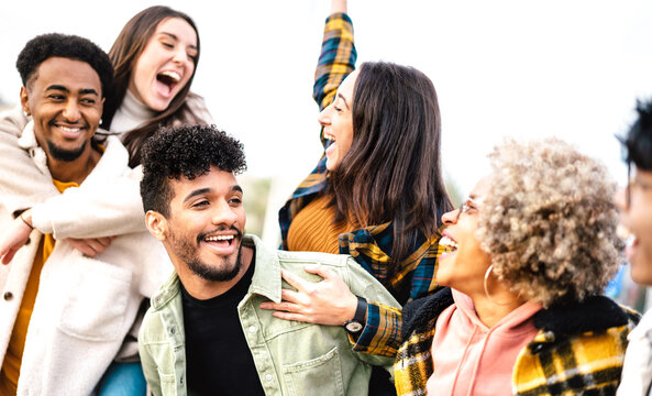 Milenial people cheering together open air on trendy life style concept - Happy guys and girls having fun outside acting piggyback move - University students on travel vacation  - Bright vivid filter