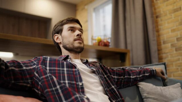 Relaxed man watching TV at home alone, leisure time, bachelor's entertainment