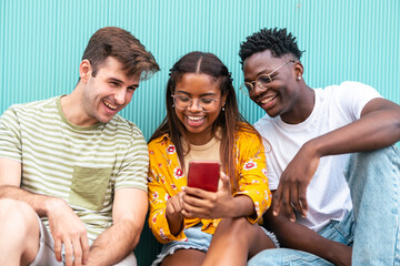 three happy young friends looking mobile phone and smiling with the content - happy teenagers with...