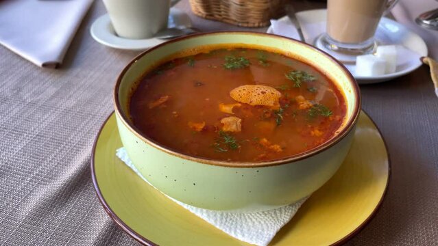 Soup solyanka on the table in the cafe. Vegetables and meat on a wooden table.