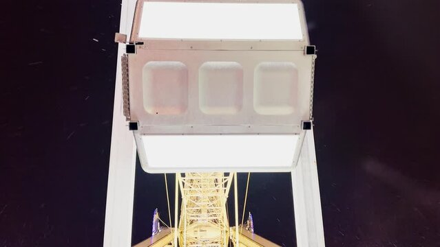 Cabins of Ferris wheel attraction move over night sky
