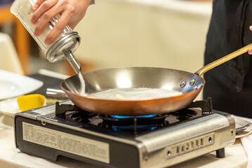 Sucre versé dans une poêle pour préparer un caramel dans un restaurant