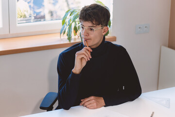 Naklejka premium Brown-haired architect is thinking hard about how to create new product designs for a new futuristic world. He works with his own creativity. Compass, pencil, ruler and paper. Creative home office