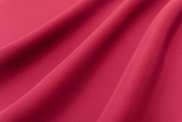 Texture of a smooth luxurious, elegant fabric in burgundy, purple, red. Purple satin or silk fabric with folds and waves
