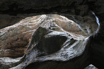 Bizarre shapes in a dark mountain gorge - with layers illuminated by the sun.
