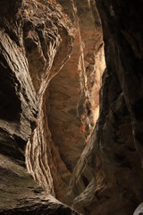 Bizarre shapes in a dark mountain gorge - with layers illuminated by the sun.