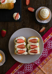 Pastel empapado en almíbar con nata montada y fresas naturales, babá al ron
