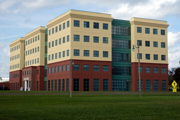 Brand new yellow, red, and green office building with a manicured, green grass lawn