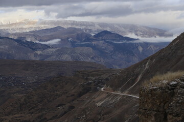 Scenic panorama: foggy mountains, cloudy sky and undulating slopes on a winter day in Dagestan.