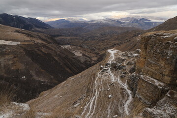 Scenic panorama: foggy mountains, cloudy sky and undulating slopes on a winter day in Dagestan.