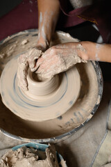 Close-up of a woman beautifully sculpts a brown clay vase on a potter's wheel, a top view