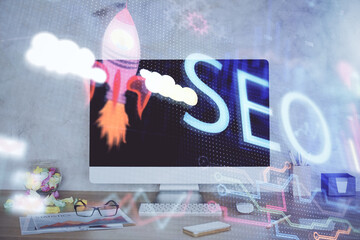 Double exposure of table with computer and seo drawing hologram. Search optimization concept.