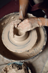 Close-up of a woman beautifully sculpts a brown clay vase on a potter's wheel, a top view