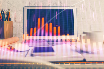 Stock market graph on background with desk and personal computer. Multi exposure. Concept of financial analysis.