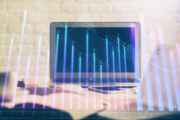 Stock market graph on background with desk and personal computer. Multi exposure. Concept of financial analysis.