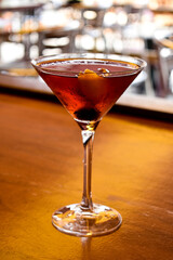 A selective focus shot of a Manhattan cocktail in a triangle cup on a bar stand