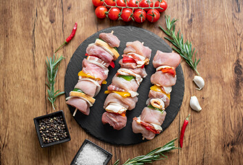 Raw meat skewers with vegetables on wooden background