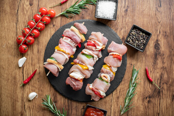 Raw meat skewers with vegetables on wooden background
