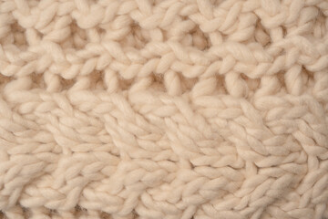 A fragment of beige knitted fabric, knitted from white sheep wool.