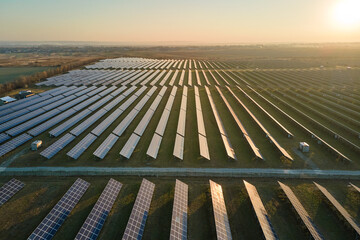 Aerial view of large sustainable electrical power plant with rows of solar photovoltaic panels for producing clean electric energy in evening. Concept of renewable electricity with zero emission