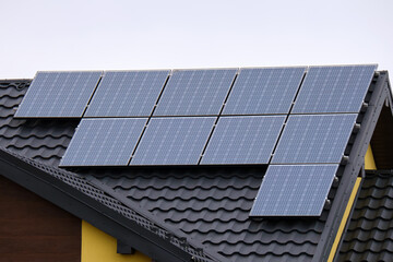 Fototapeta premium Residential house with rooftop covered with solar photovoltaic panels for producing of clean ecological electrical energy in suburban rural area. Concept of autonomous home