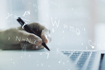 Double exposure of creative scientific formula concept with hand writing in notebook on background with laptop, research and development concept