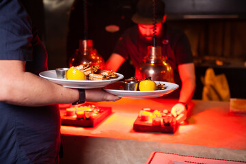A waiter serves shrimp in a restaurant. The chef is cooking in the background
