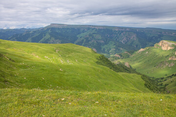 Panoramic landscape - the Bermamyt plateau in Karachay-Cherkessia with green grass, beautiful hills and the horizon line in a hazy haze and space to copy