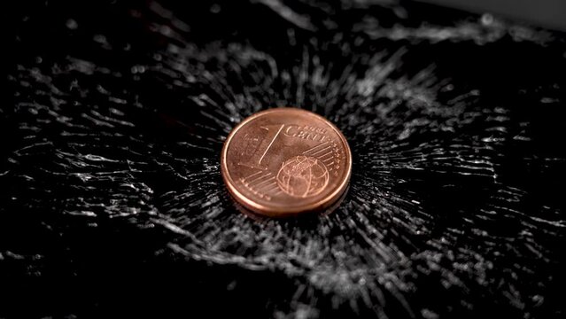 One cent European coin on a black crushed cracked surface. Concept of economic crisis