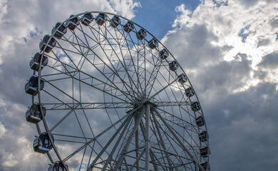 A new metal Ferris wheel with booths on the background of a blue cloudy sky in Vladimir Park Russia on a summer day and a space for copying