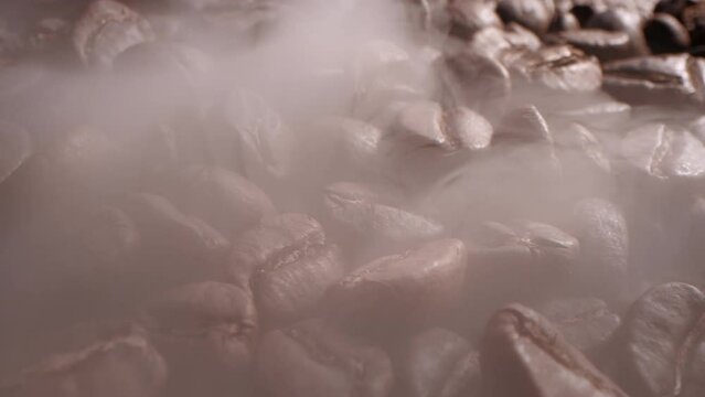 Fragrant coffee beans are roasted in frying pan,smoke comes from coffee beans. Macro shot coffee bean roasting moke coming from coffee bean roasting.Soft diffuse smoke coming from roasted coffee beans