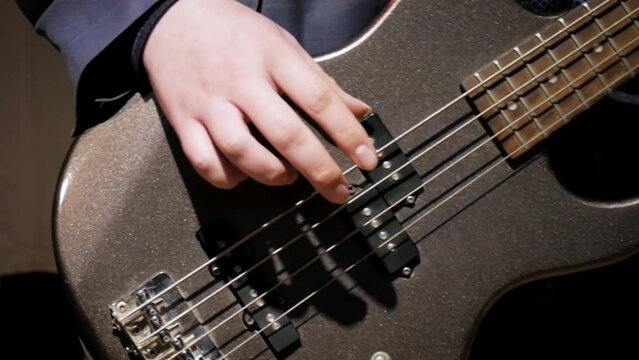 Man playing bass in slow motion. Stock. Closeup video with hands and guitar musician performs at home. Stay home education concept.
