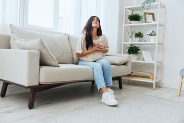 Woman sitting on sofa at home arm and shoulder pain, muscle sprain and joint pain, calcium problems in bones