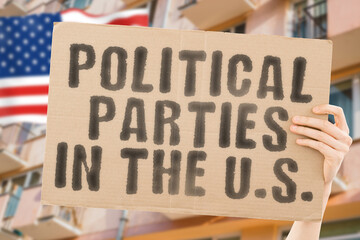 The phrase " Political parties in the U.S. " is on a banner in men's hands with blurred background. Elections. Election. Elects. Elect. Improvement. Improve. Renovation. Renewal. Renovate. Transform