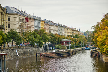 Naklejka premium Historic buildings on the banks of the water canal in Prague in autumn.