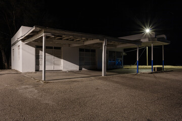 Abandoned vintage service station at night with street light - obrazy, fototapety, plakaty