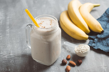 Banana smoothie with protein powder and nuts in a glass jar, healthy eating concept - obrazy, fototapety, plakaty