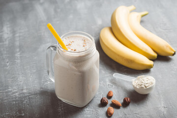 Banana smoothie with protein powder and nuts in a glass jar, healthy eating concept