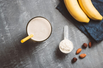 Banana smoothie with protein powder and nuts in a glass, top view, healthy eating concept