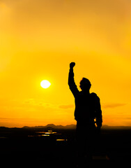 Raised fist of a man in protest. It is silhouetted at sunset on top of a mountain. Protest concept black lives matter. Vertical photo. Copy space on top