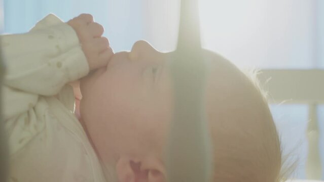 Close-up view of mother dressing her little newborn baby in cribe. Woman putting on clothes on baby in slow-motion