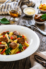Pasta with roasted pork loin, spinach and parmesan on wooden table 