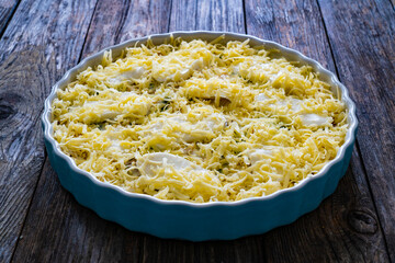 Uncooked noodle casserole with roast pork loin, mozzarella cheese, bechamel sauce and spinach on wooden table

