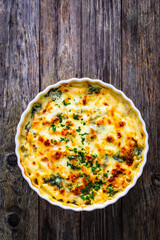 Noodle casserole with roast pork loin, mozzarella cheese, bechamel sauce and spinach on wooden table
