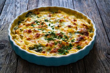 Noodle casserole with roast pork loin, mozzarella cheese, bechamel sauce and spinach on wooden table
