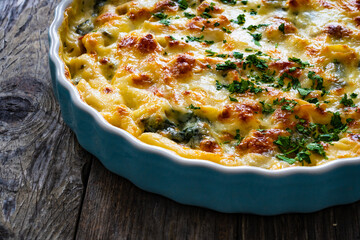 Noodle casserole with roast pork loin, mozzarella cheese, bechamel sauce and spinach on wooden...