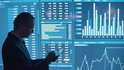 Man writing data on tablet from big digital screen. Back view of businessman in official suit in monitoring room processing analytics feed, looking at charts. Occupation, modern technology concept - Powered by Adobe