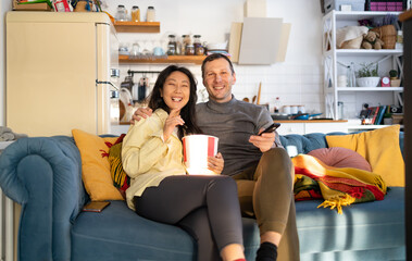Happy young couple preparing to watch a movie at home.