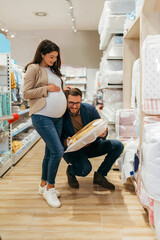 Attractive middle age couple enjoying in buying clothes and bed sheets for their new baby....
