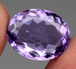 Natural gemstone purple amethyst on gray background